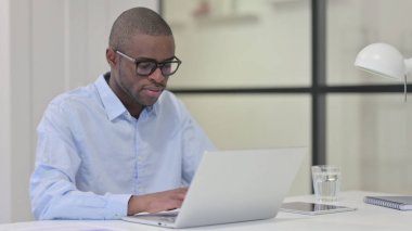 Ofisteki dizüstü bilgisayarda çalışan Afrikalı Adam 