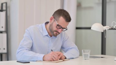 Orta Yaşlı Adam İşyerinde Kağıda Yazıyor 