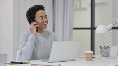 Dizüstü bilgisayarlı Afrikalı Kadın Akıllı Telefonla Konuşuyor 