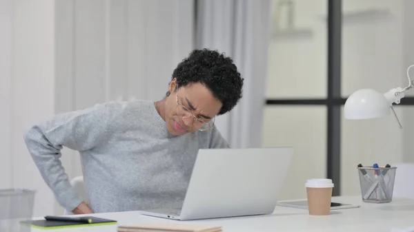 ノートパソコンを使いながら腰痛を持つアフリカ人女性 — ストック写真