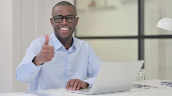 Polegares para cima por homem africano com laptop no trabalho — Fotografia de Stock