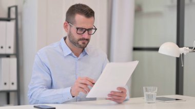 Orta Yaşlı Adam İş Başında Belgeler Okuyor 