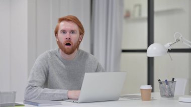 Kızıl Sakallı Adam dizüstü bilgisayar kullanırken şok olmuş hissediyor 