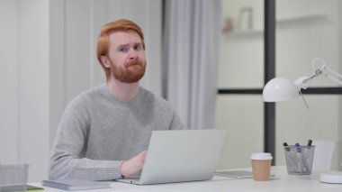 Dizüstü bilgisayarlı kızıl saçlı sakallı adam 
