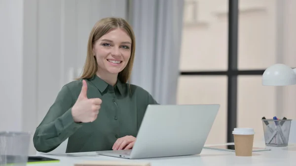 Pollici su da giovane donna con computer portatile al lavoro — Foto Stock