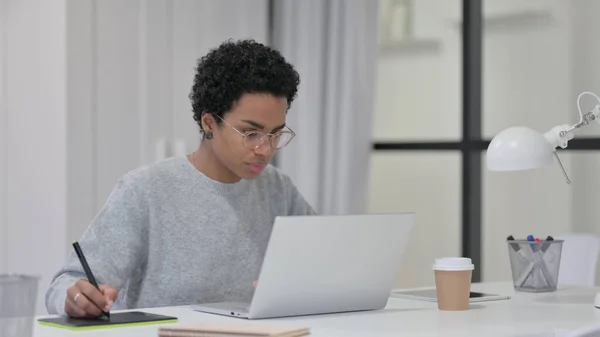 ノートパソコンを使いながらタブレットでデザインするアフリカ人女性 — ストック写真
