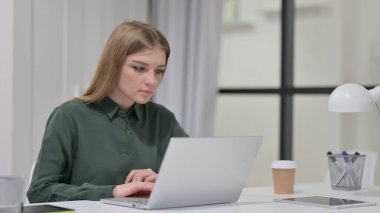 Ofisteki dizüstü bilgisayarda çalışan genç kadın. 