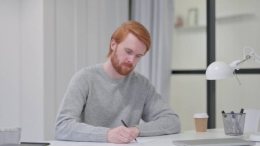 Genç Sakallı Kızıl Adam İşyerinde Kağıt Yazıyor 