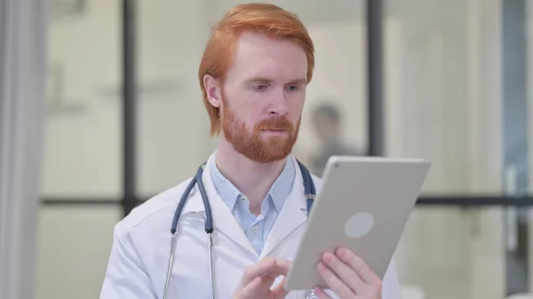 Kızıl saçlı erkek doktor iş yerinde tablet kullanıyor. — Stok fotoğraf