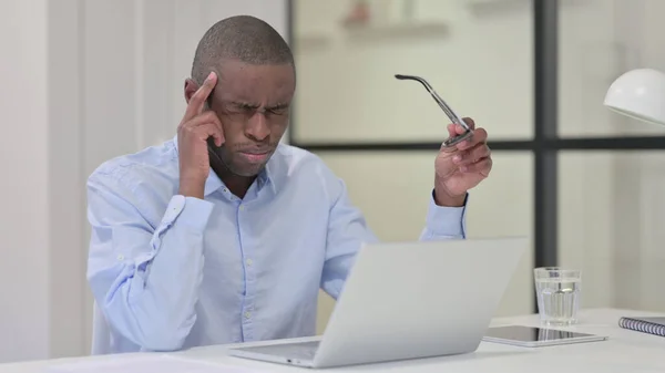 Afrikaanse Man met hoofdpijn tijdens het typen op laptop — Stockfoto