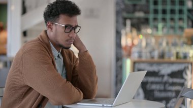 Kafede dizüstü bilgisayar kullanırken Afrikalı Adam Düşünüyor 