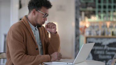 Cafe 'de dizüstü bilgisayar kullanırken öksüren Afrikalı Adam 