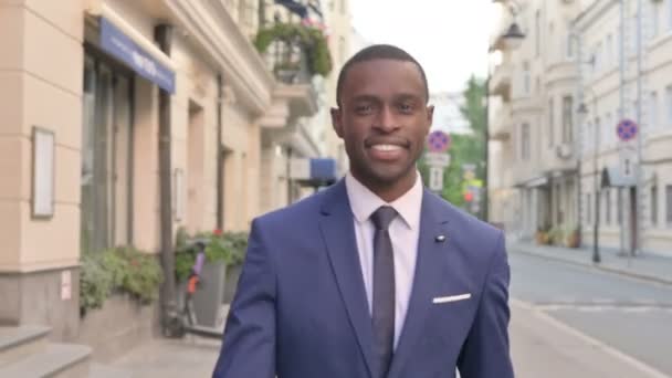 Närbild av leende afrikanska affärsman promenader på gatan — Stockvideo