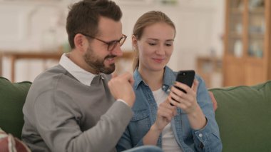 Mutlu çift evde akıllı telefon kullanıyor.