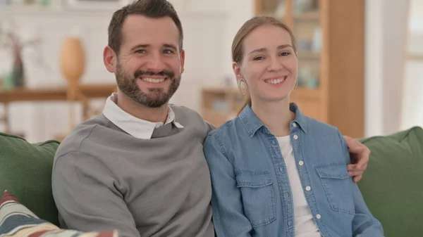 Happy Couple Smiling at the Camera while Sitting on Sofa — Stock Photo, Image