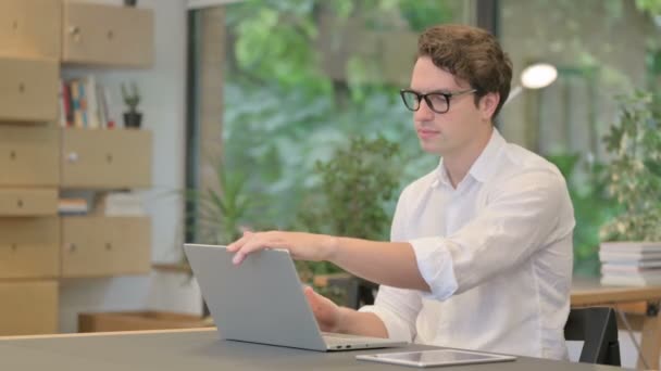 Jonge man sluit laptop en verlaat moderne kantoor — Stockvideo
