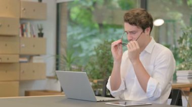 Modern Ofiste dizüstü bilgisayarla uğraşırken Genç Adam 'ın başı ağrıyor.