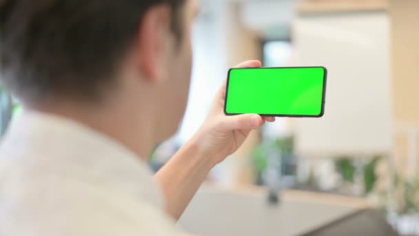 Молодий чоловік дивиться на смартфон з екраном "Зеленої хромосоми". — стокове відео