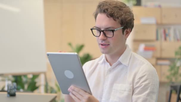 Retrato de videollamada en la tableta por el joven en la oficina moderna — Vídeos de Stock