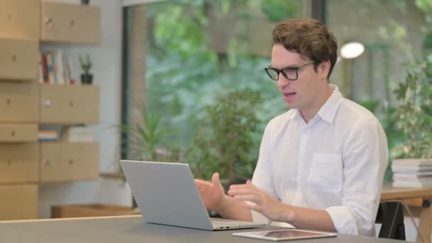 Giovane uomo che reagisce alla perdita durante l'utilizzo del computer portatile in ufficio moderno — Video Stock