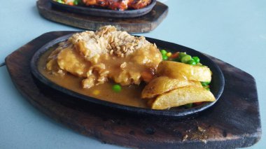 Sos ve patates dilimli kızarmış tavuk bezelye ve sebzelerle servis edilir. Sıcak, iştah açıcı bir atmosfer yaratır. Günlük yemek ve yemek sunumu için mükemmeldir..