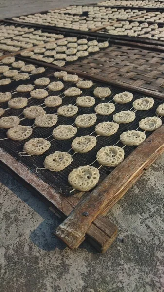 Nilüfer kökü parçaları açık havada örgü tepsilerde kurutuluyor. Güneş ışığı geleneksel çerez üretimi için doğal ve kırsal bir atmosfer yaratıyor..