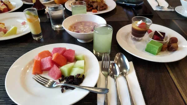 Tabaklara ve bardaklara yerleştirilmiş çeşitli renkli meyve tatlıları ve içecekler şık bir yemek düzeninde taze ve davetkar bir atmosfer yaratıyor. Yemek ve konukseverlik pazarlaması için mükemmel..