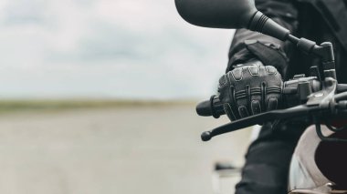 Koruyucu motosiklet eldivenli bir adamın elinde siyah bir motosiklet var.