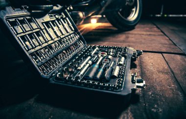 Tool box on a wooden floor against the background of a motorcycle wheel