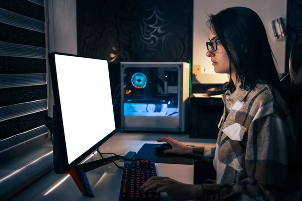 一个戴着眼镜的年轻的黑发女子坐在家里的电脑前 在家工作 远程工作 那女孩玩电子游戏 — 图库照片