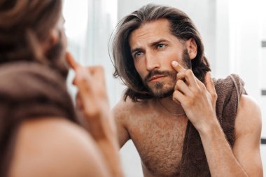 İnsan aynadaki yansımasına dikkatlice bakar, cilt bakımına.