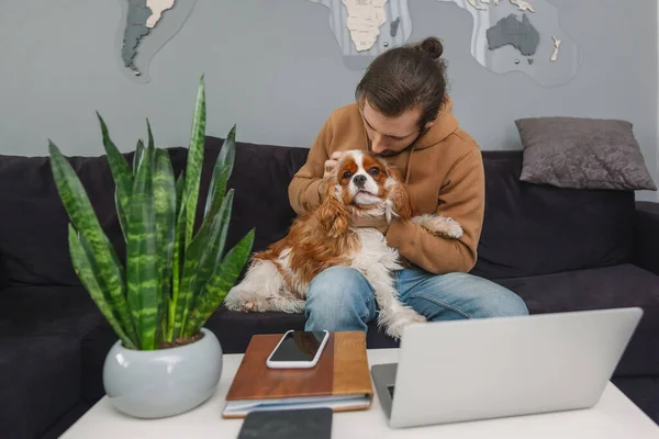 İşten sonra koltukta oturan bir adam bir köpeği okşuyor.