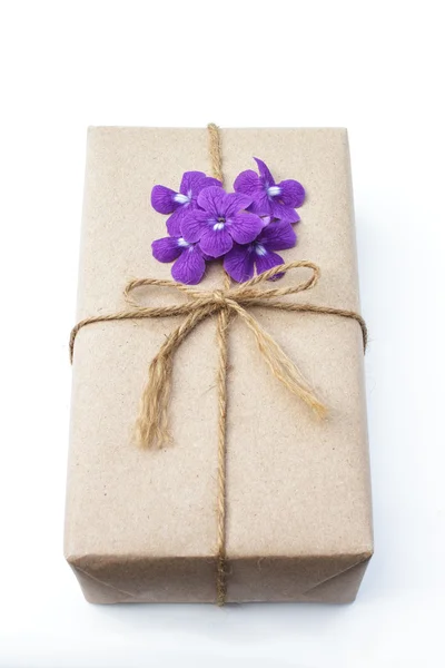 Geschenk box-pakket omwikkeld met papier en touw met paarse bloemen — Stockfoto