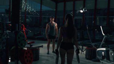 Genç adam ve kadın kas spor salonu makinede esneme