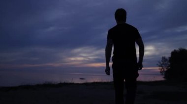 Bir gün batımı kumsalda yürüyen yalnız adam