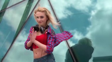 Gençler boş zamanlarını dışarıda eğlenerek geçiriyorlar. Cam inşaatın önünde dans figürleri gösteren güzel bir genç kız. Sokak kültürü kavramı, yaşam tarzı.