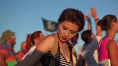 Gün batımında rock konserindeki kalabalık arasında dans eden Asyalı güzel bir kız. Müzik hayranları yaz konserinin tadını çıkarıyor. Gençlik kültürü ve eğlence anlayışı.