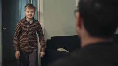 Genç baba sonunda işten eve geliyor. Babasına koşan ve ona sarılan sıradan giysili mutlu ergen oğlanın yakın çekimi. Gülümseyen oğul, akşam babasını kapıda karşılıyor. Mutluluk kavramı.