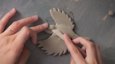 Çömlekçi kadınların el sanatları yapan bir kuşun ayrıntıları üzerinde çalışmalarını yakından izleyin. Yaratıcı seramik kavramı. Farklı çömlek aletleriyle çalış. İş kurma, sanat eseri ve iç mekan