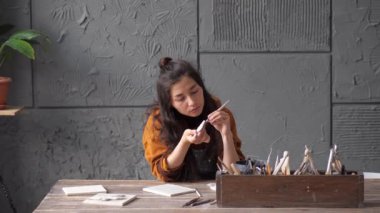 Güzel Asyalı çömlekçi kadın kil el sanatları ile ilgili detaylar üzerinde çalışıyor. Farklı çömlek aletleriyle çalış. Yaratıcı eğlence zamanı ve seramik kavramı. Küçük bir iş, sanat eseri ve iç mekan kuracağız.