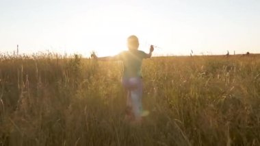 Küçük çocuk altın ışıkta bir uçak modeliyle koşuyor. Gün batımında arka planda oyuncak bir uçakla koşan mutlu bir çocuk. Mutlu aile kavramı. Çocukluk hayalleri