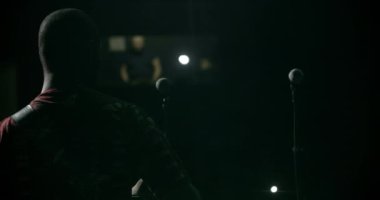 Siyahi müzisyen arkada durup performans sergiliyor. Kayıt stüdyosundaki adamın izole edilmiş arka görüntüsü. Karanlık konser salonunda gitar çalan erkek afro silueti. Rock grubu konsepti