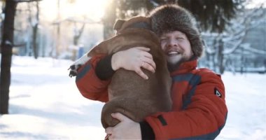 Gülümseyen sakallı adamın sevimli arkadaşına sarılıp nazikçe öptüğü İngiliz bulldogu. Kışın dışarıda saf köpeğiyle eğlenen adamın portresi. Hayvanlar, hayvanlar, insan dostluğu
