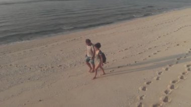 Romantik çiftin hava aracı görüntüsü gün batımının arka planında birbirlerine bakıyor. Aşık bir çift okyanus boyunca yürüyor. Aşıklar öpüşür, romantik yolculukta el ele tutuşur..