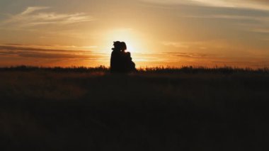 Altın tarlada bir çift silueti ve güzel bir günbatımı. Genç ve romantik bir aile eğleniyor. Yaz akşamları erkek, kadını sevgiyle kucağına alır. İnsanlar kalpten konuşuyor ve sarılıyorlar. İki kişi..