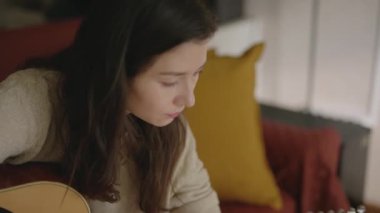 Müzisyen olmak isteyen biri dizüstü bilgisayarla müzik aleti çalmayı öğreniyor. Evde kal, tek başına takıl güzel kız online ders izliyor ve müzik çalışıyor. Genç Asyalı kadın evde gitar çalıyor..