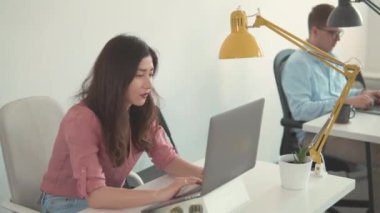 İnternette laptop kullanan bir iş kadını. Güzel, güler yüzlü, kendine güvenen genç bir kadın başarılı bir ticaret operasyonu yaptı. Kadın işçi ev ofisindeki ekrana bakıyor. Mutlu Milenyum Asyalı etnik köken kız öğrencileri.