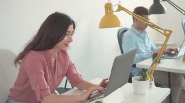 Kadın işçi ev ofisindeki ekrana bakıyor. Mutlu Milenyum Asyalı etnik köken kız öğrencileri. İnternette laptop kullanan bir iş kadını. Güzel gülümseyen, kendine güvenen genç bir kadın başarılı bir ticaret operasyonu yaptı..