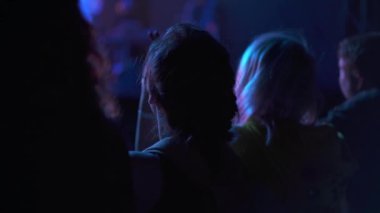 İnsanlar ellerini kaldırıp şarkı söylüyorlar. Rock konserinde dans eden bir kızın silueti. Hayranları ve yıldızları olan bir gece kulübünde canlı performans. Eğlence ve geçmiş kavramı.