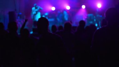 Hayranları ve yıldızları olan bir gece kulübünde canlı performans. Eğlence ve geçmiş kavramı. İnsanlar ellerini kaldırıp şarkı söylüyorlar. Rock grubu konserinde dans eden bir kızın silueti..